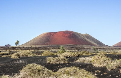 During the day, the blue sky, the brown mountains near the green grass
